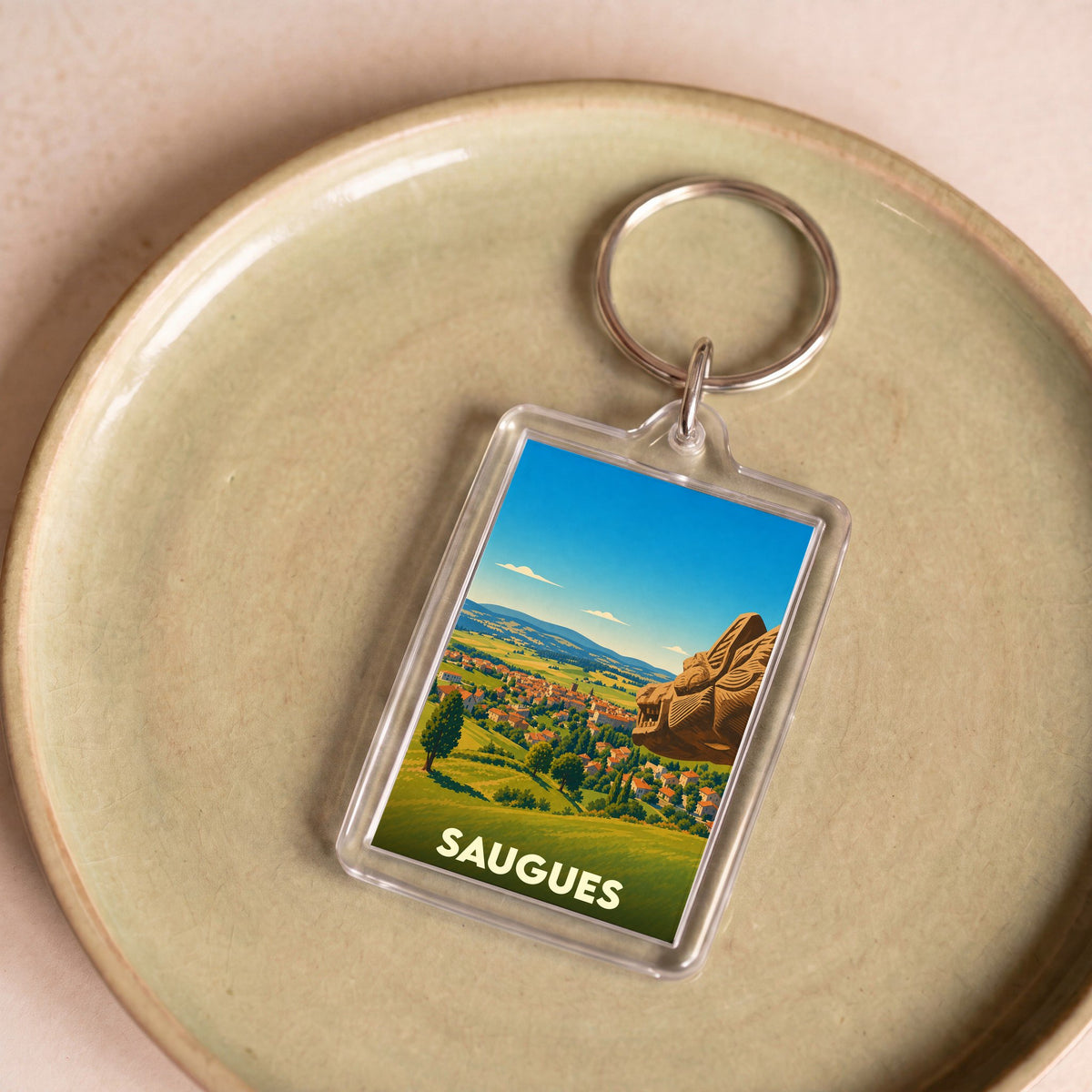 Porte-clés souvenir de la ville de Saugues avec une illustration stylisée.