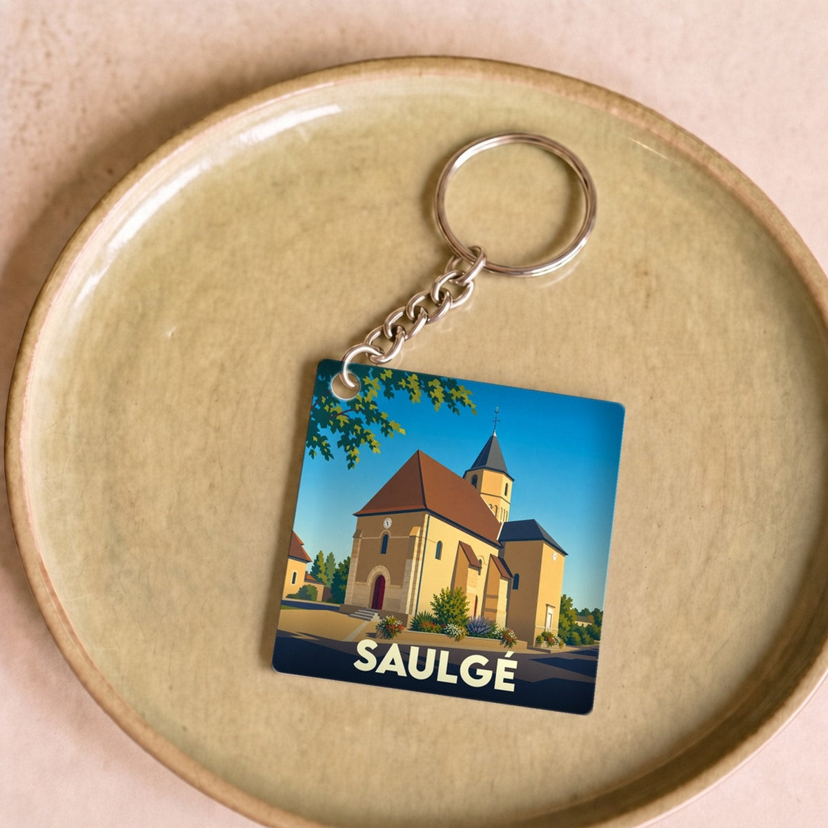 Porte-clés souvenir de la ville de Saulgé avec une illustration stylisée de son église.