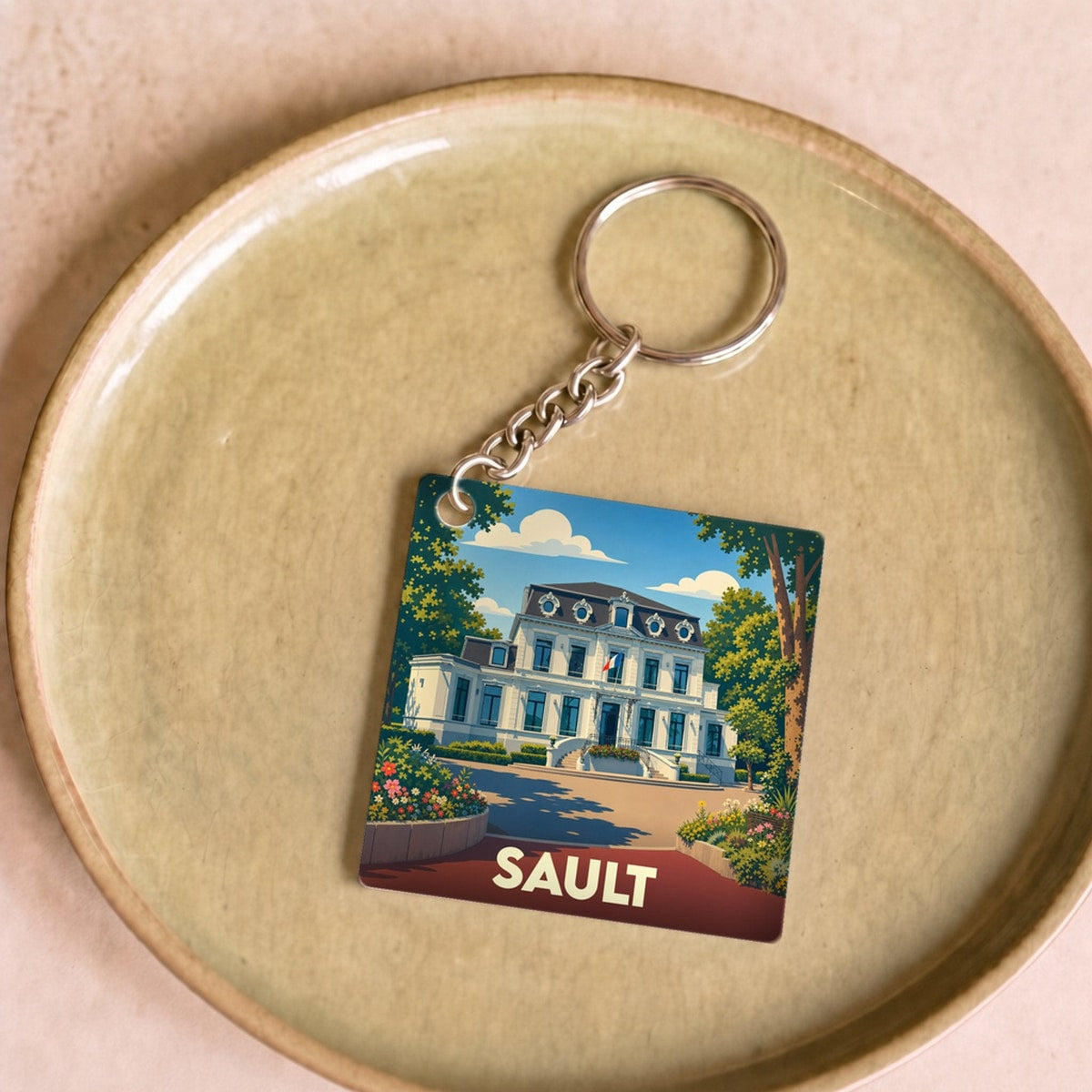 Porte-clés souvenir de la ville de Sault avec une illustration stylisée de sa mairie.