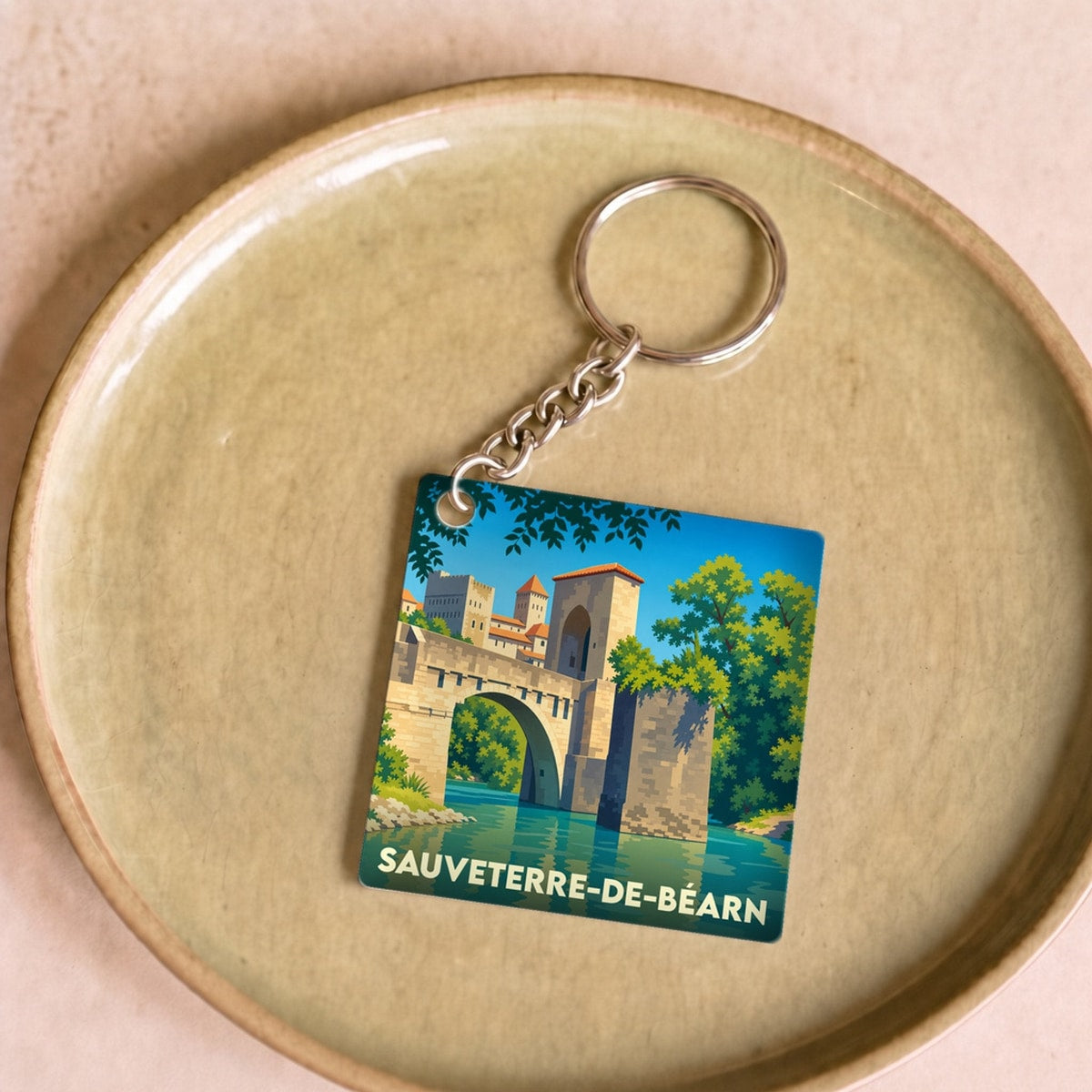 Porte-clés souvenir de la ville de Sauveterre-de-Béarn avec une illustration stylisée de son pont fortifié.