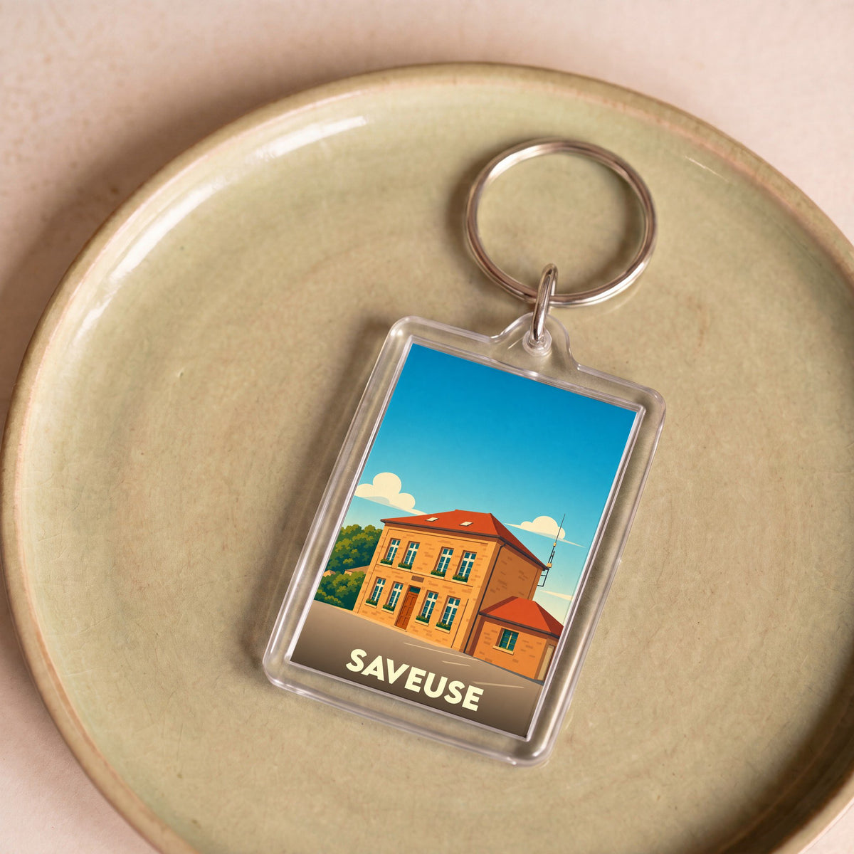 Porte-clés souvenir de la ville de Saveuse avec une illustration stylisée d'un bâtiment local.