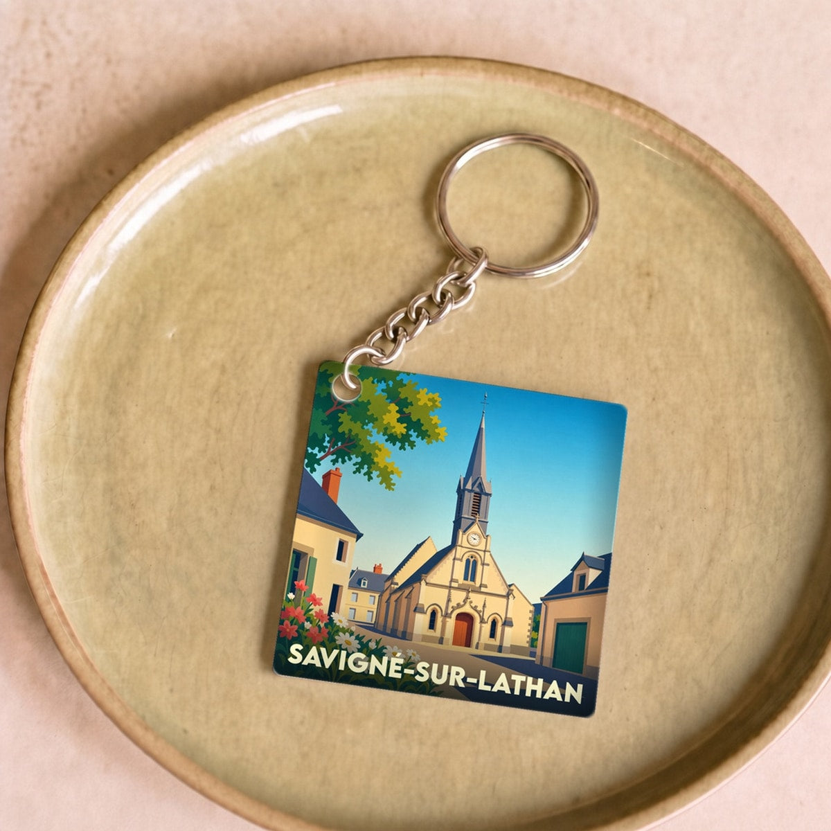 Porte-clés souvenir de la ville de Savigné-sur-Lathan avec une illustration stylisée.