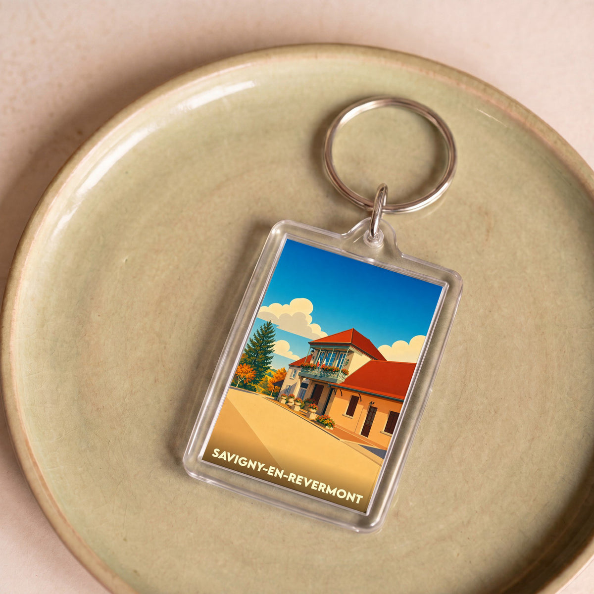 Porte-clés souvenir de la ville de Savigny-en-Revermont avec une illustration stylisée.