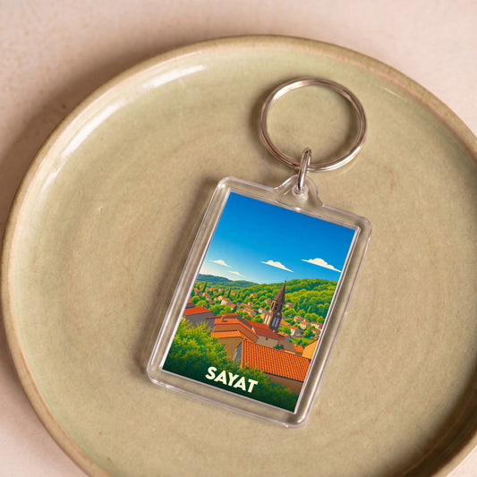 Porte-clés souvenir de la ville de Sayat avec une illustration stylisée de ses toits et de son clocher.