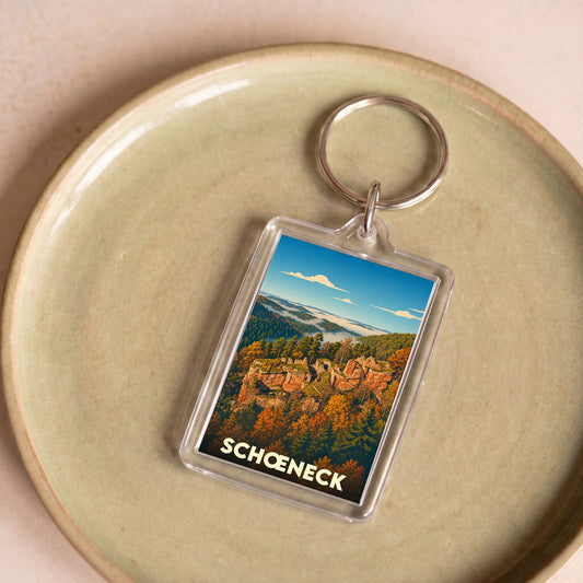Porte-clés souvenir de la ville de Schœneck avec une illustration stylisée de son paysage forestier et rocheux.