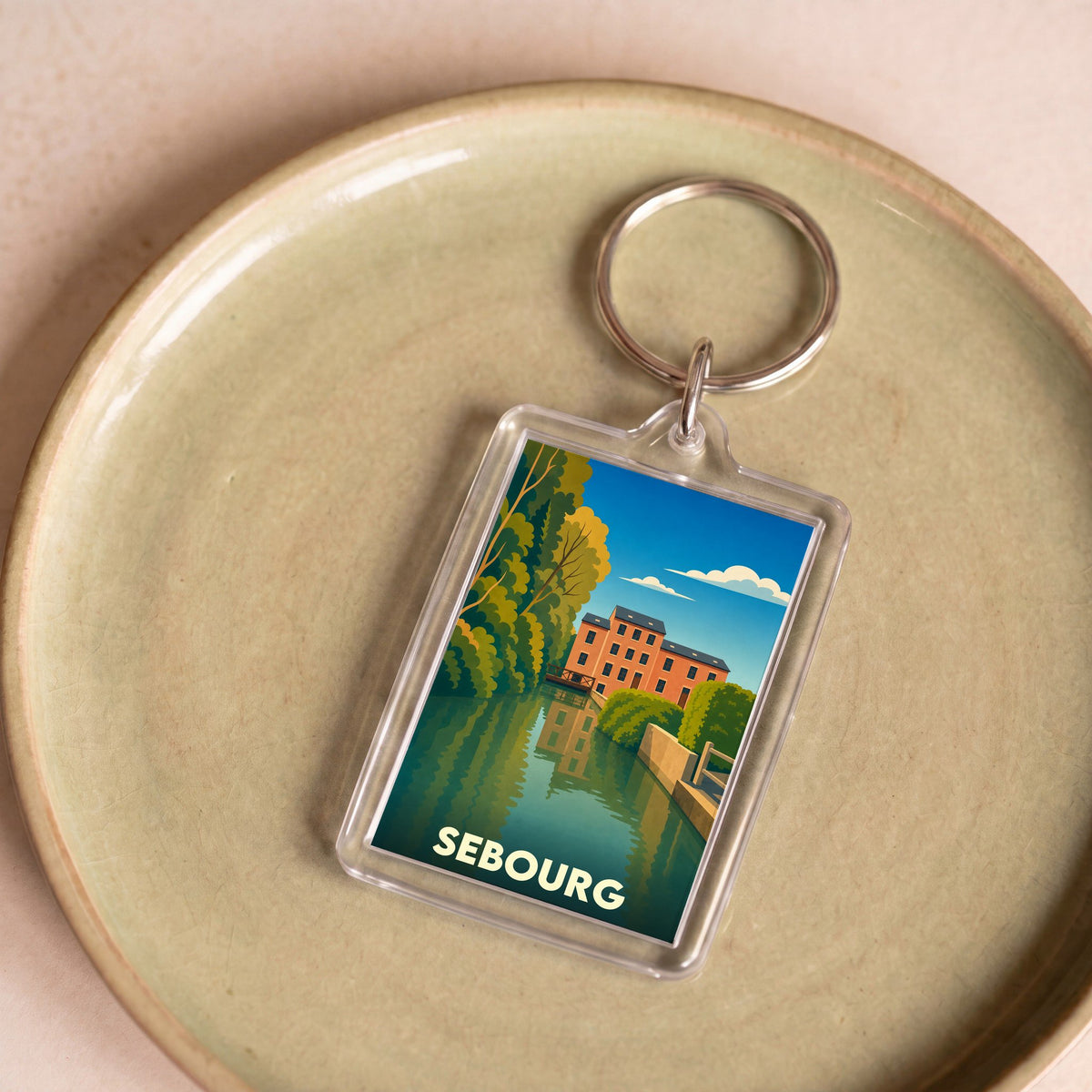 Porte-clés souvenir de la ville de Sebourg avec une illustration stylisée.