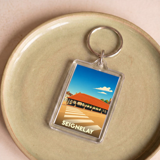 Porte-clés souvenir de la ville de Seignelay avec une illustration stylisée.