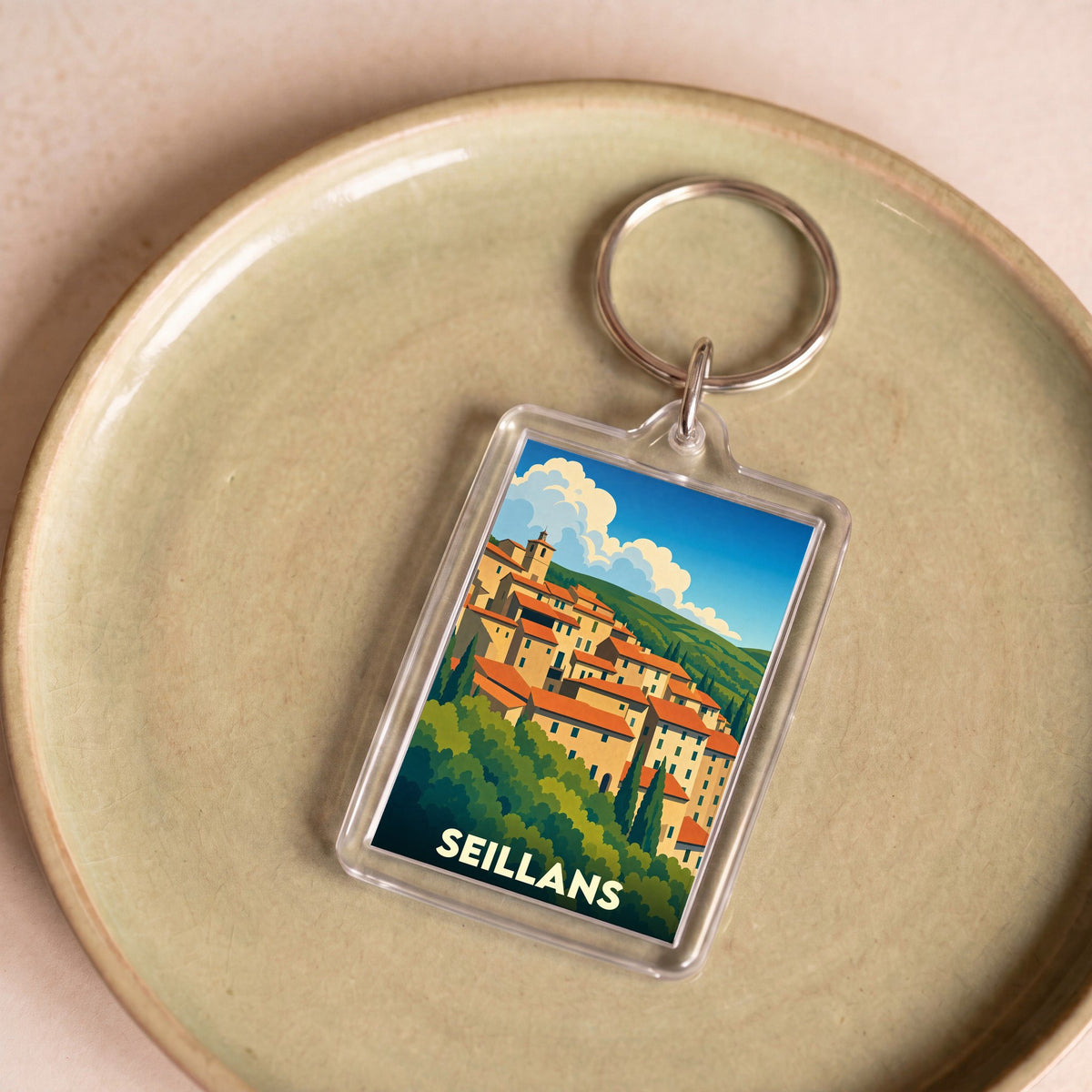 Porte-clés souvenir de la ville de Seillans avec une illustration stylisée de ses maisons provençales.
