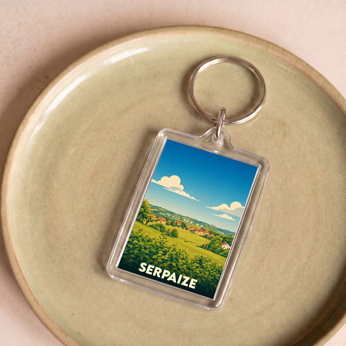 Porte-clés souvenir de la ville de Serpaize avec une illustration stylisée de son paysage rural.