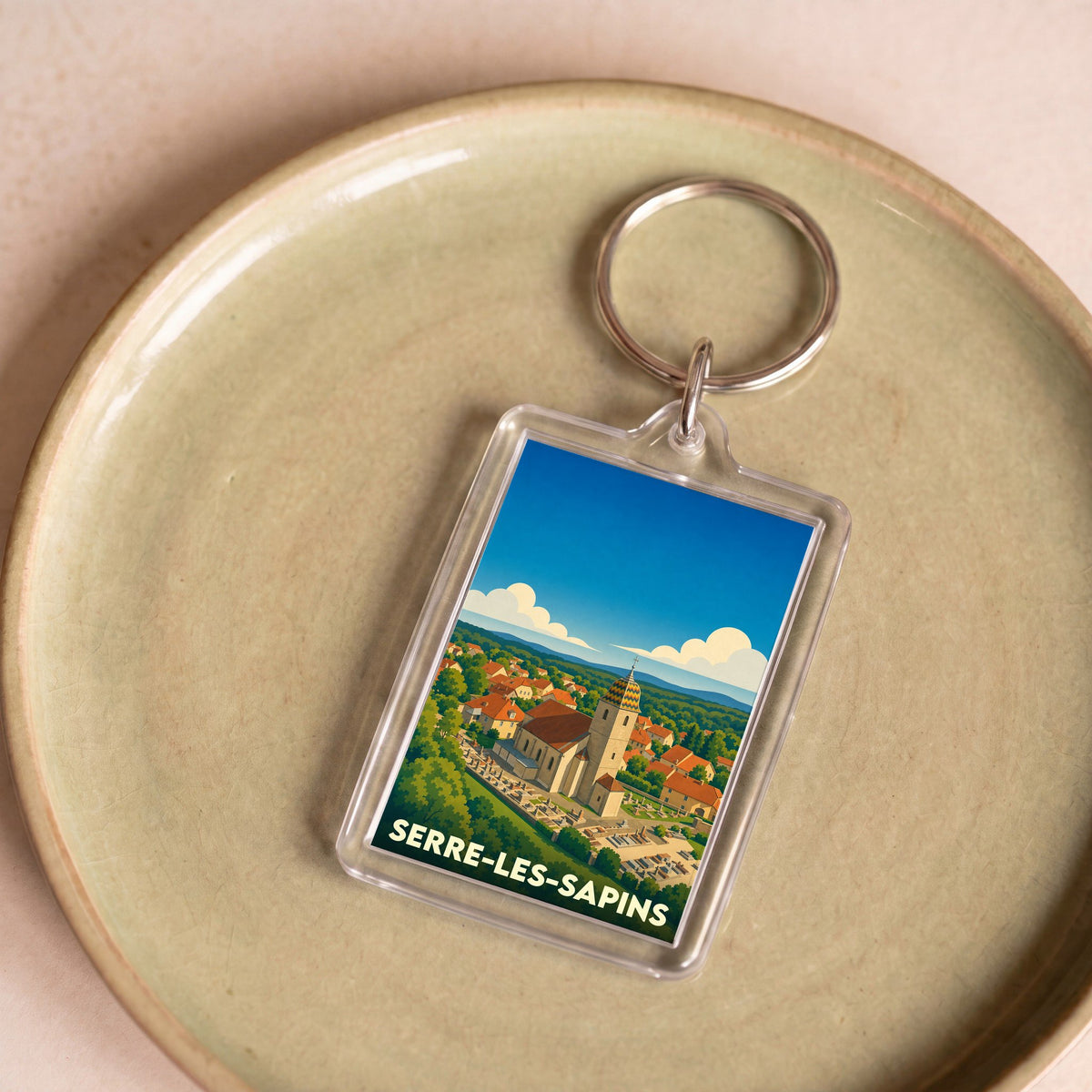 Porte-clés souvenir de la ville de Serre-les-Sapins avec une illustration stylisée.