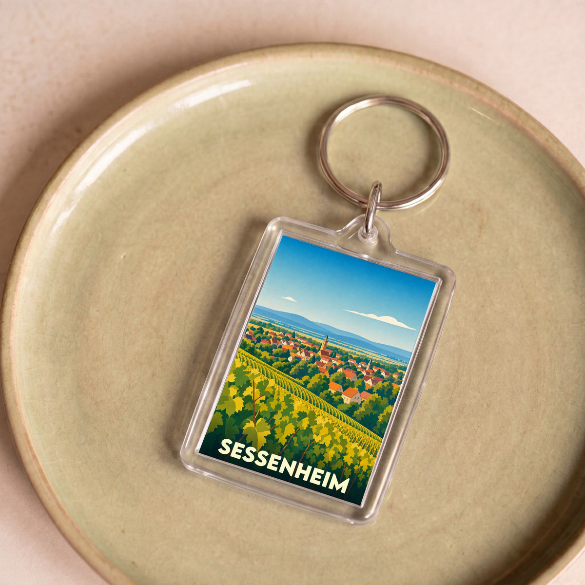 Porte-clés souvenir de la ville de Sessenheim avec une illustration stylisée de vignobles et du village.