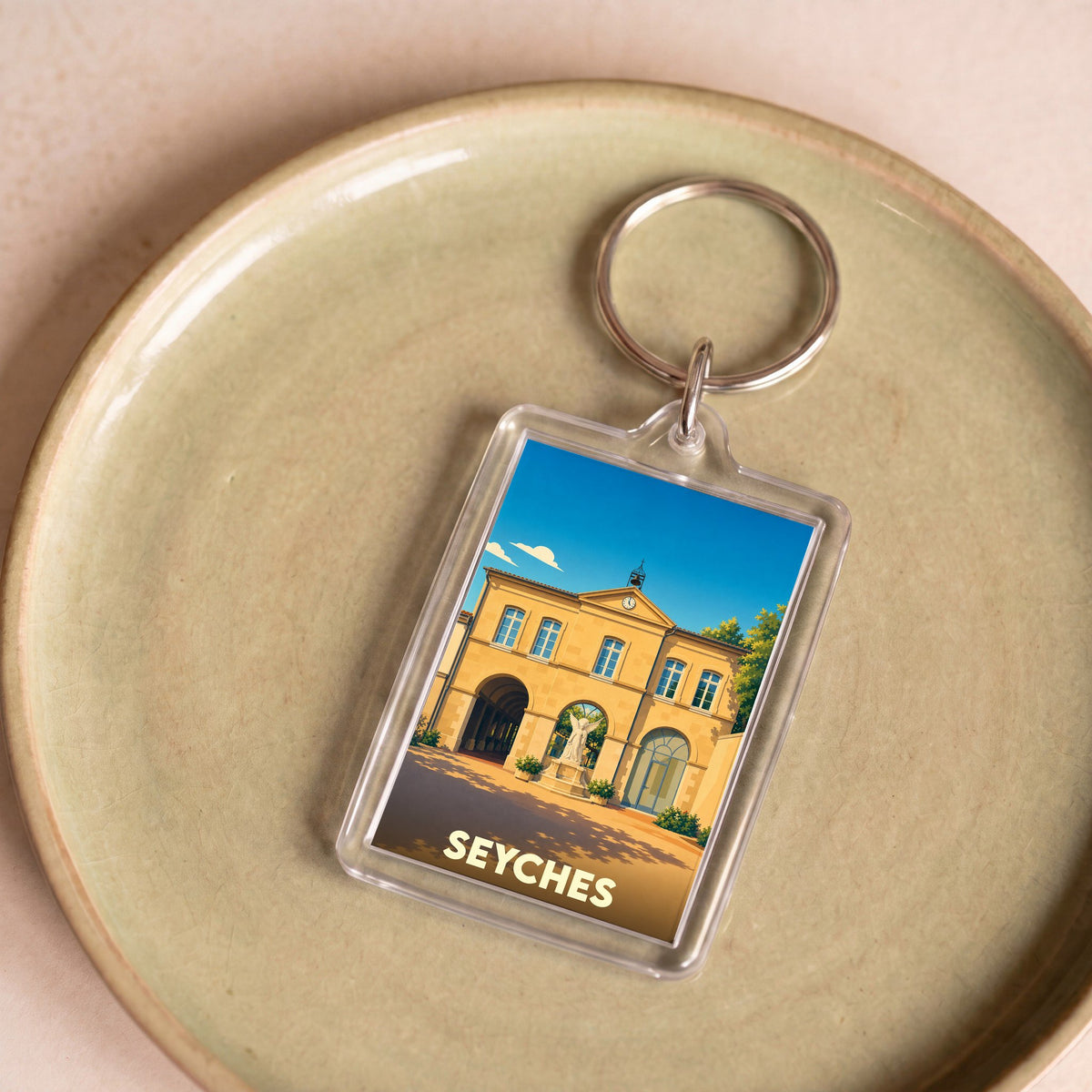 Porte-clés souvenir de la ville de Seyches avec une illustration stylisée d'un bâtiment historique.