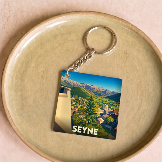 Porte-clés souvenir de la ville de Seyne avec une illustration stylisée d'un paysage montagneux.