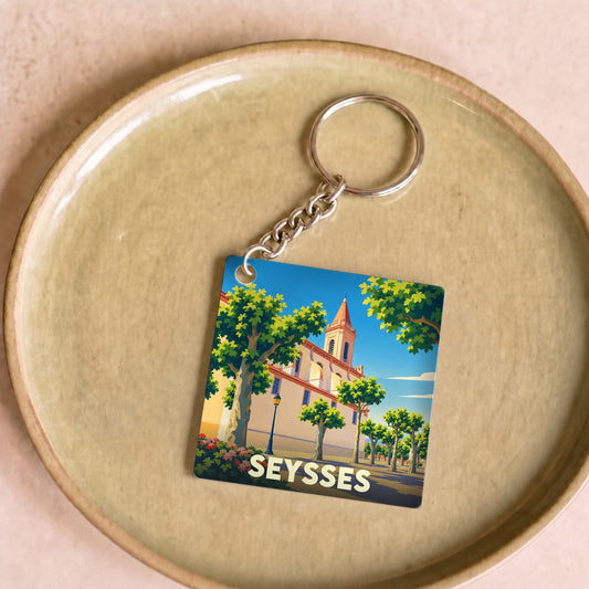Porte-clés souvenir de la ville de Seysses avec une illustration stylisée de son église entourée d'arbres.