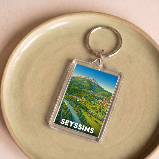 Porte-clés souvenir de la ville de Seyssins avec une illustration de paysage panoramique.