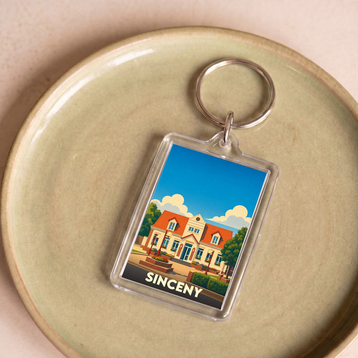 Porte-clés souvenir de la ville de Sinceny avec une illustration stylisée de sa mairie.