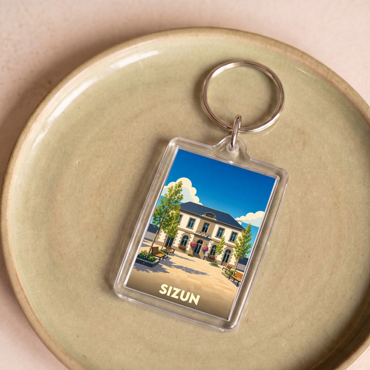 Porte-clés souvenir de la ville de Sizun avec une illustration stylisée d'un bâtiment emblématique.