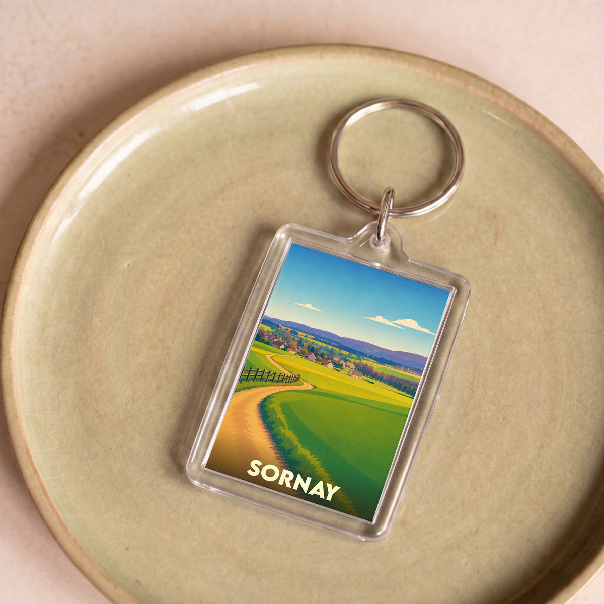 Porte-clés souvenir de la ville de Sornay avec une illustration champêtre stylisée.