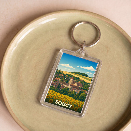 Porte-clés souvenir de la ville de Soucy avec une illustration stylisée de son paysage urbain et d'un champ de tournesols.