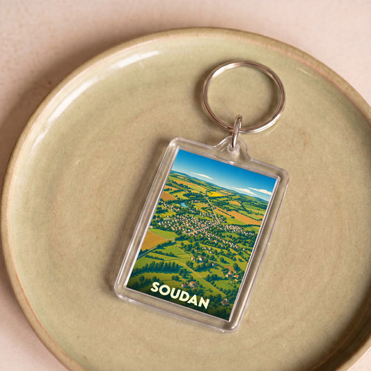 Porte-clés souvenir de la ville de Soudan avec une illustration aérienne stylisée de son paysage rural.