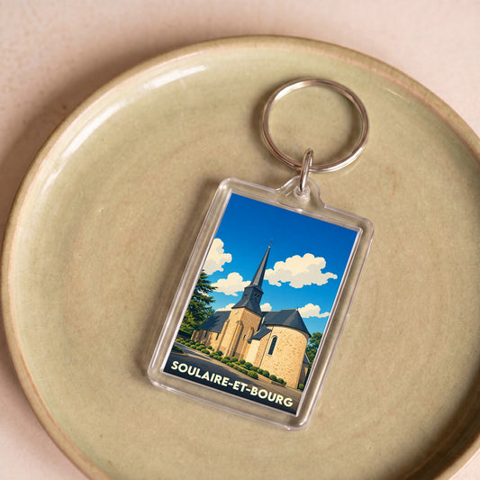 Porte-clés souvenir de la ville de Soulaire-et-Bourg avec une illustration stylisée de son église.