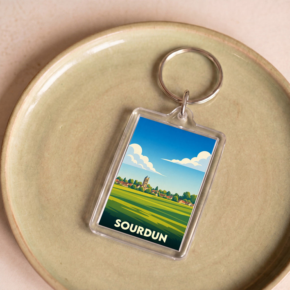 Porte-clés souvenir de la ville de Sourdun avec une illustration stylisée de son paysage.