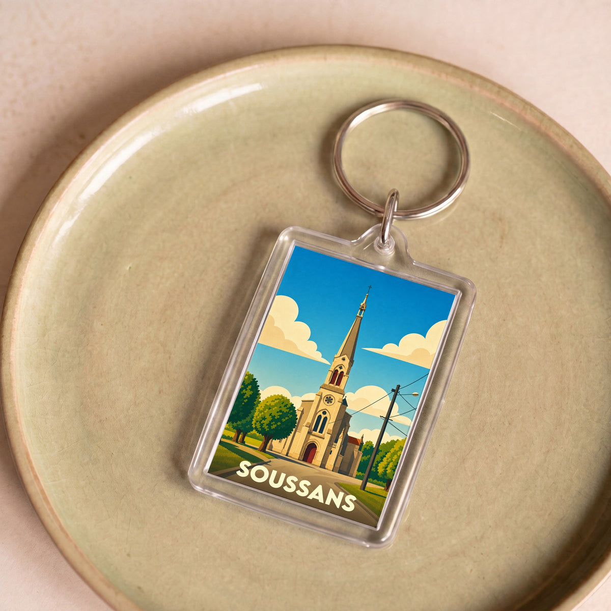 Porte-clés souvenir de la ville de Soussans avec une illustration stylisée de son église.