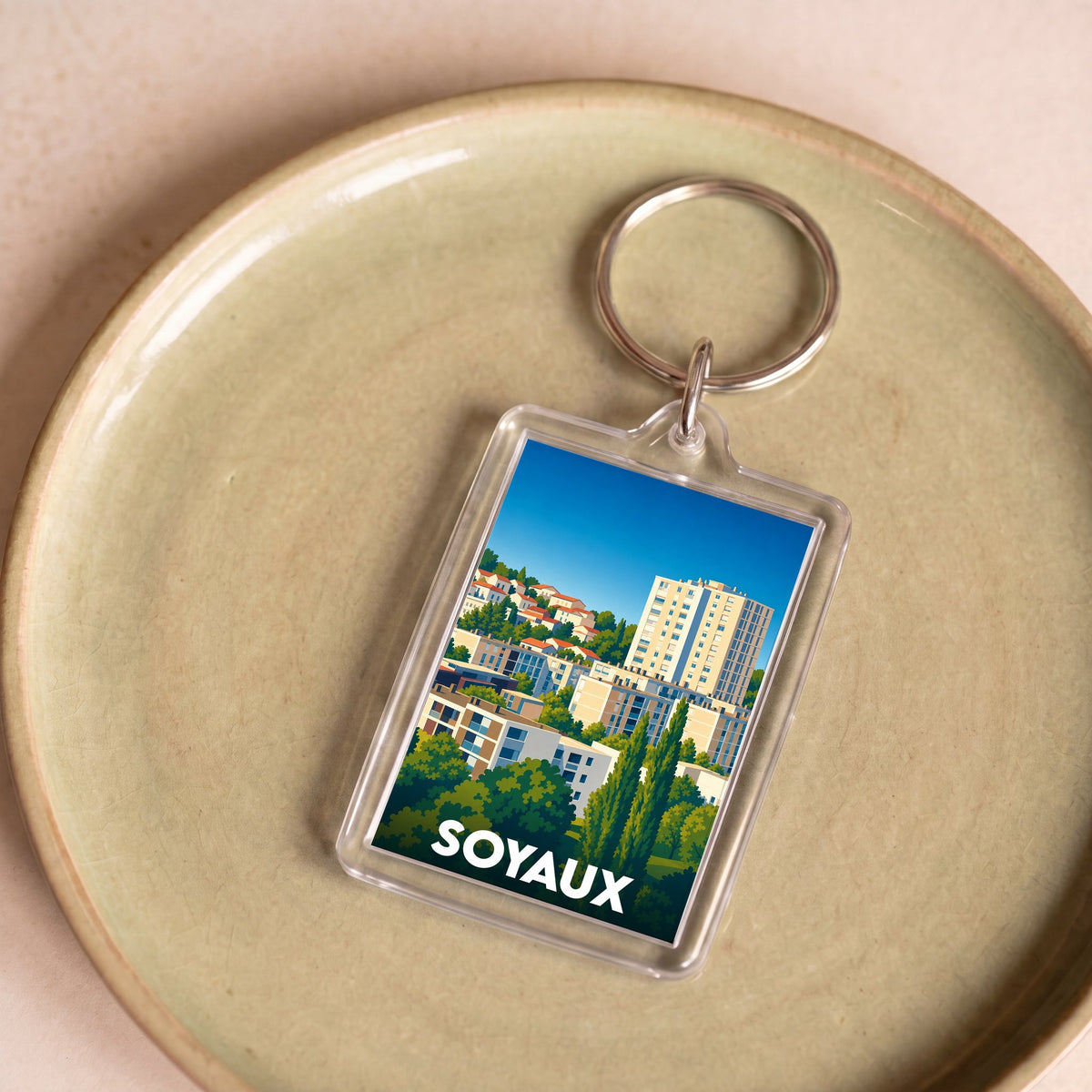 Porte-clés souvenir de la ville de Soyaux avec une illustration urbaine colorée.