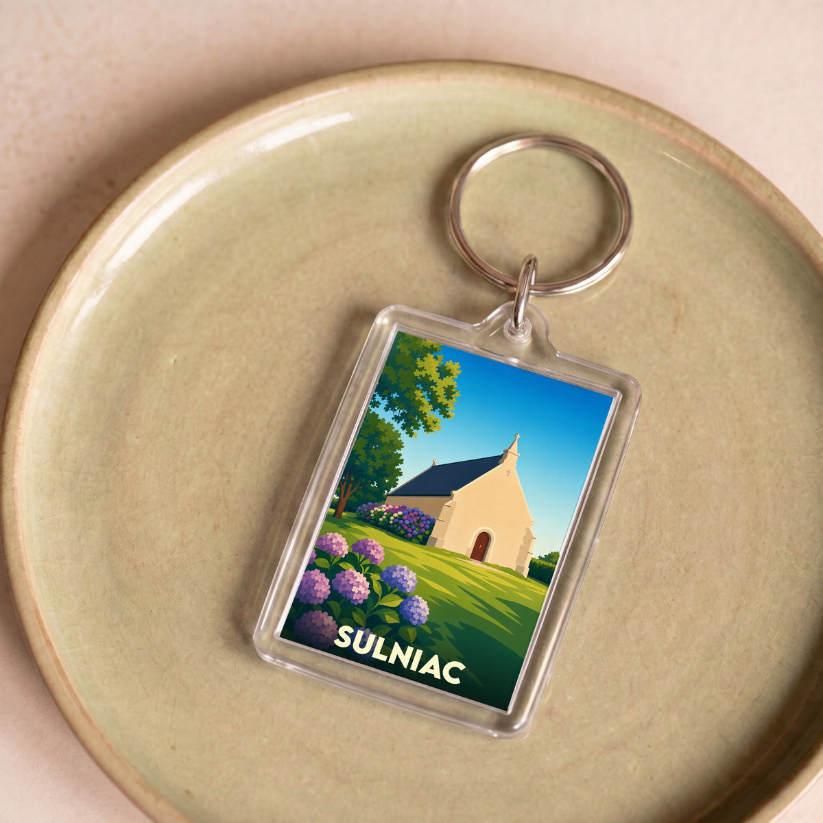 Porte-clés souvenir de la ville de Sulniac avec une illustration stylisée d'une chapelle entourée de fleurs.