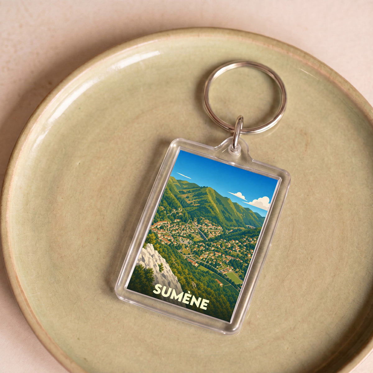 Porte-clés souvenir de la ville de Sumène avec une illustration stylisée de ses paysages montagneux.