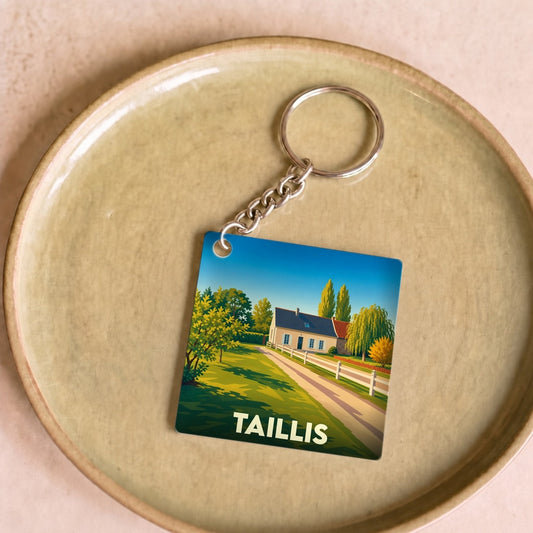Porte-clés souvenir de la ville de Taillis avec une illustration stylisée de paysage rural.