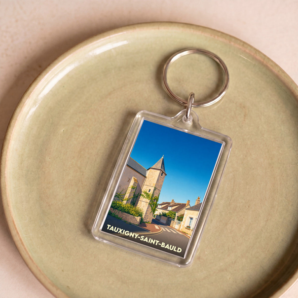 Porte-clés souvenir de la commune de Tauxigny-Saint-Bauld avec une illustration stylisée.