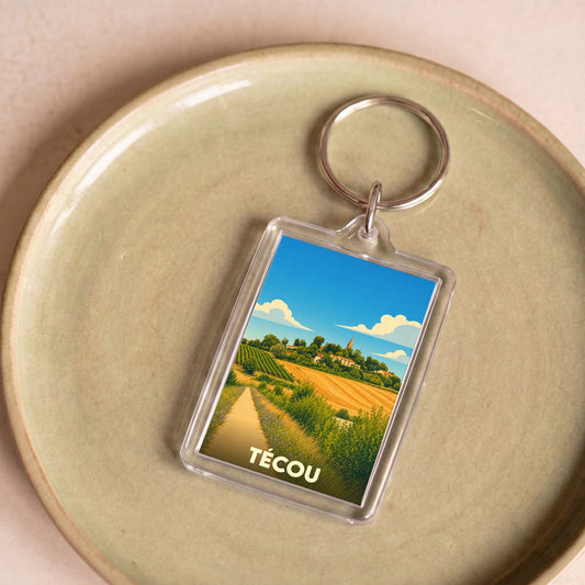 Porte-clés souvenir de la ville de Técou avec une illustration stylisée de son paysage rural.