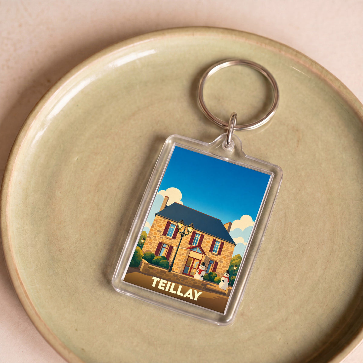 Porte-clés souvenir de la ville de Teillay avec une illustration stylisée d'un bâtiment en pierre.