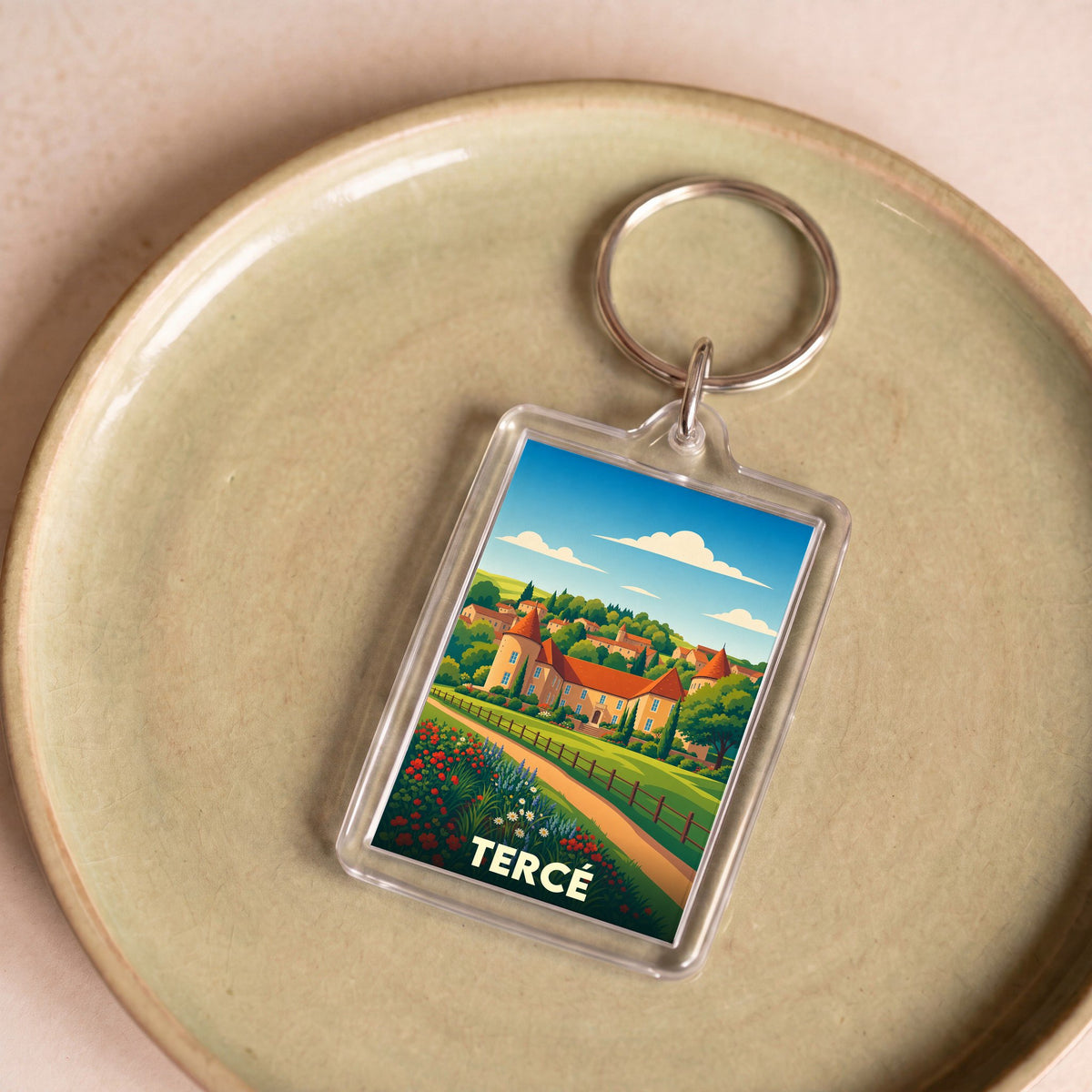 Porte-clés souvenir de la ville de Tercé avec une illustration stylisée d'un paysage champêtre.