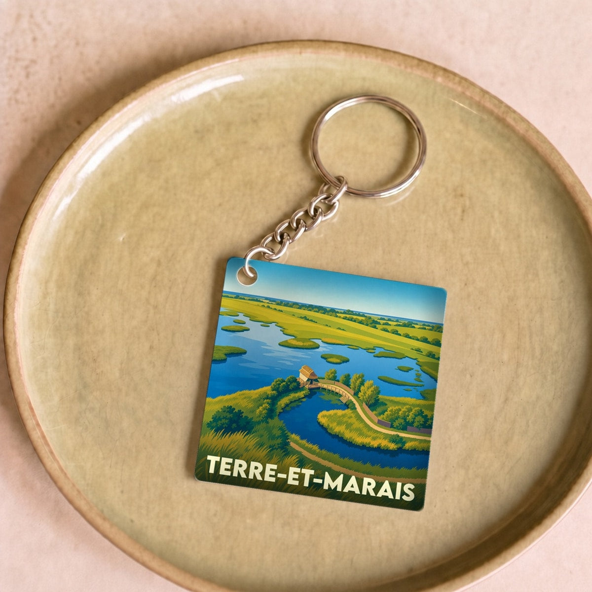 Porte-clés souvenir de la ville de Terre-et-Marais avec une illustration stylisée de ses paysages.