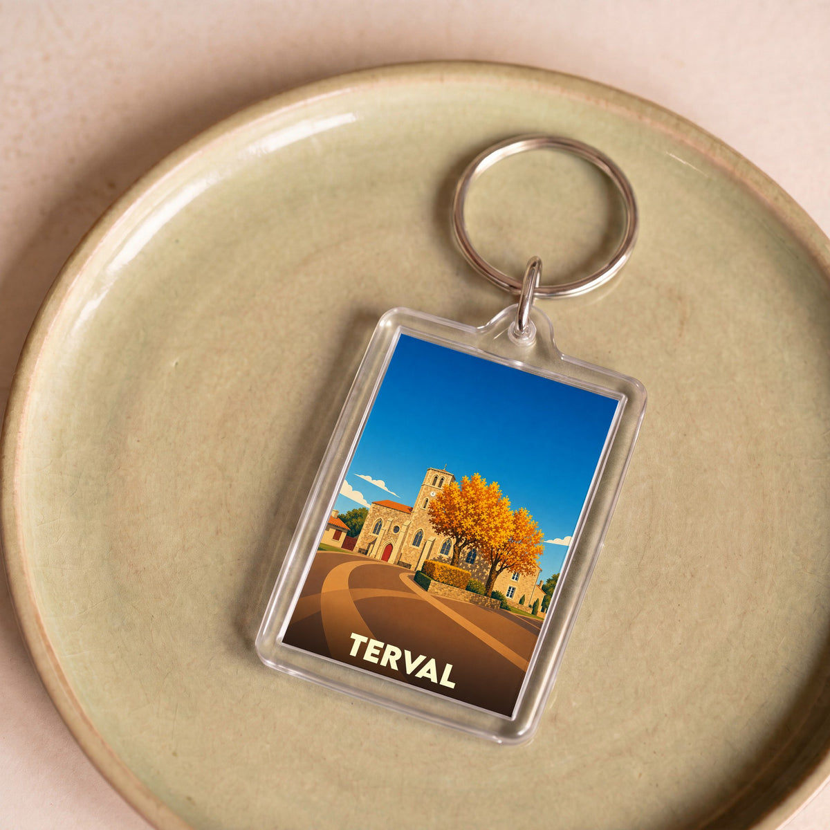 Porte-clés souvenir de la ville de Terval avec une illustration stylisée d'une église et d'un arbre d'automne.