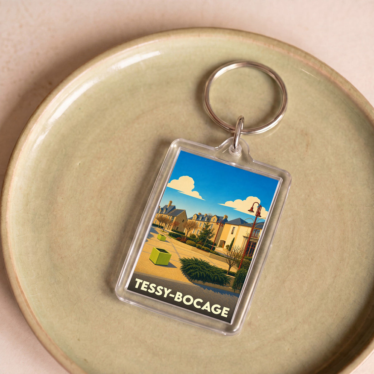 Porte-clés souvenir de la ville de Tessy-Bocage avec une illustration stylisée.