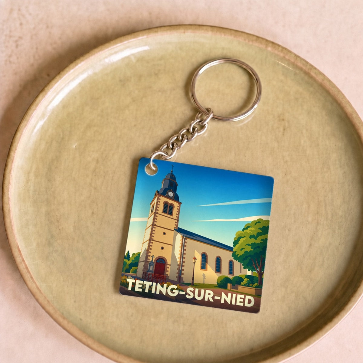 Porte-clés souvenir de la ville de Teting-sur-Nied avec une illustration stylisée de son église.