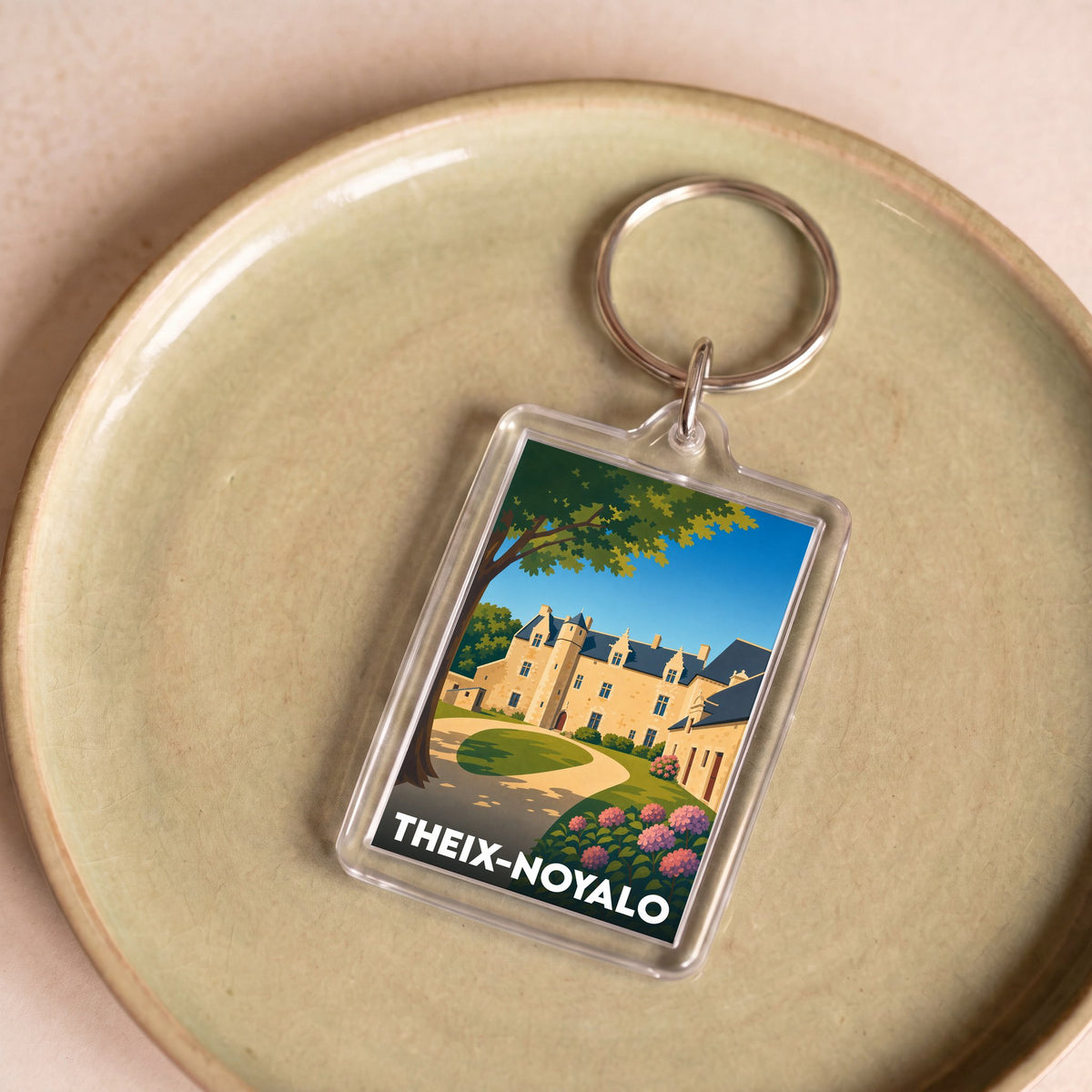 Porte-clés souvenir de la ville de Theix-Noyalo avec une illustration stylisée d'un château.