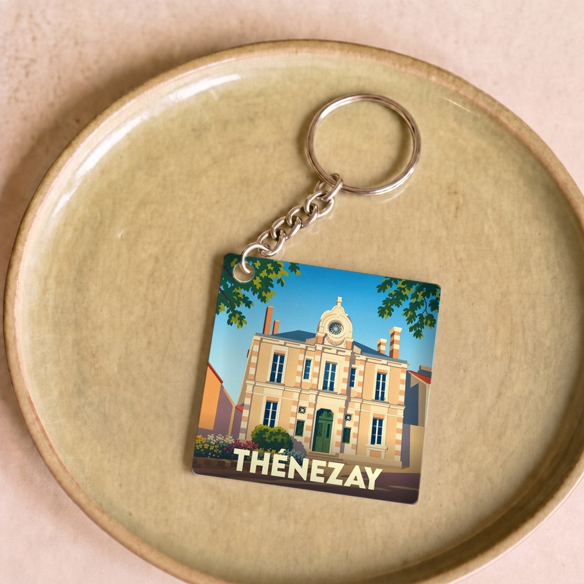 Porte-clés souvenir de la ville de Thénezay avec une illustration stylisée de son hôtel de ville.