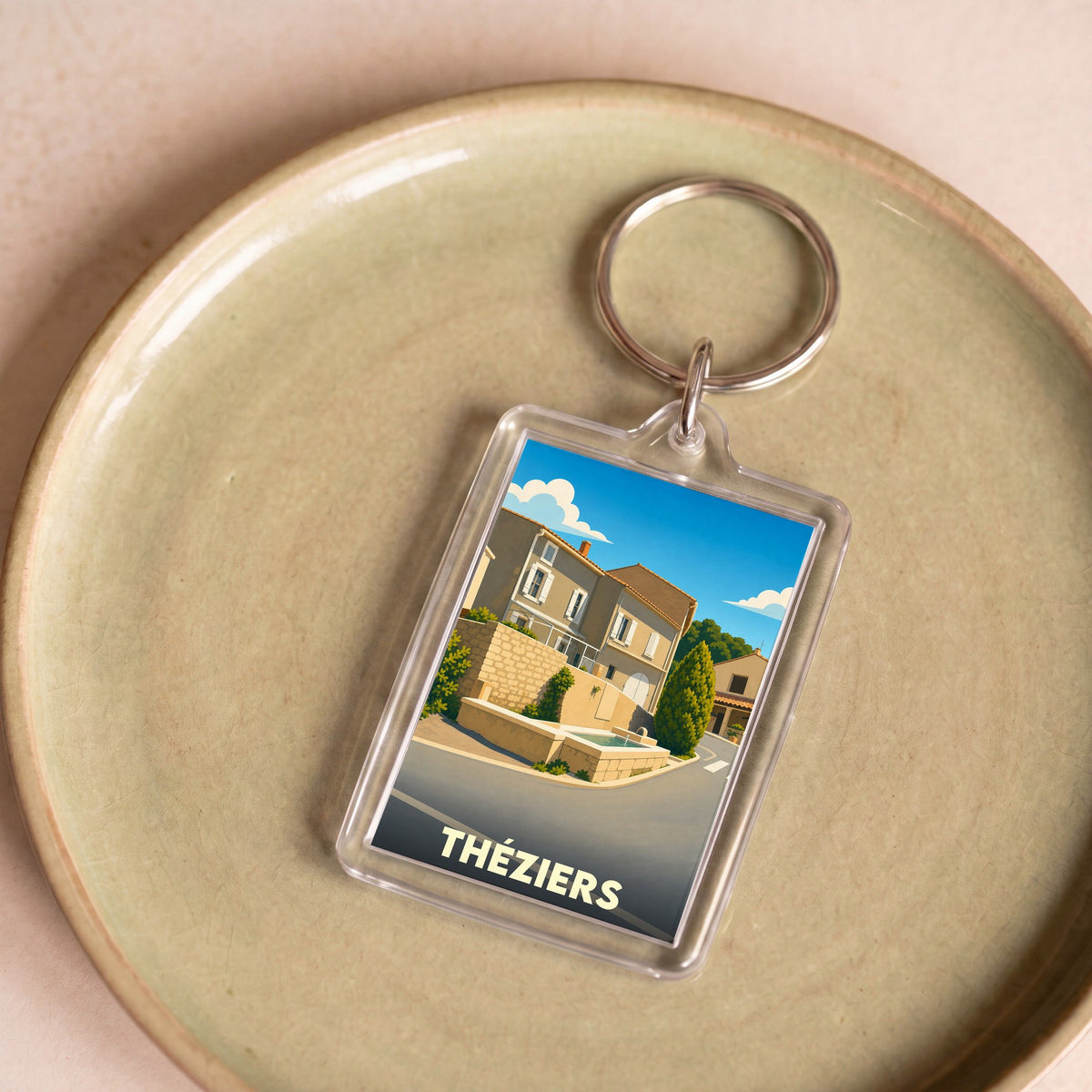 Porte-clés souvenir de la ville de Théziers avec une illustration stylisée.