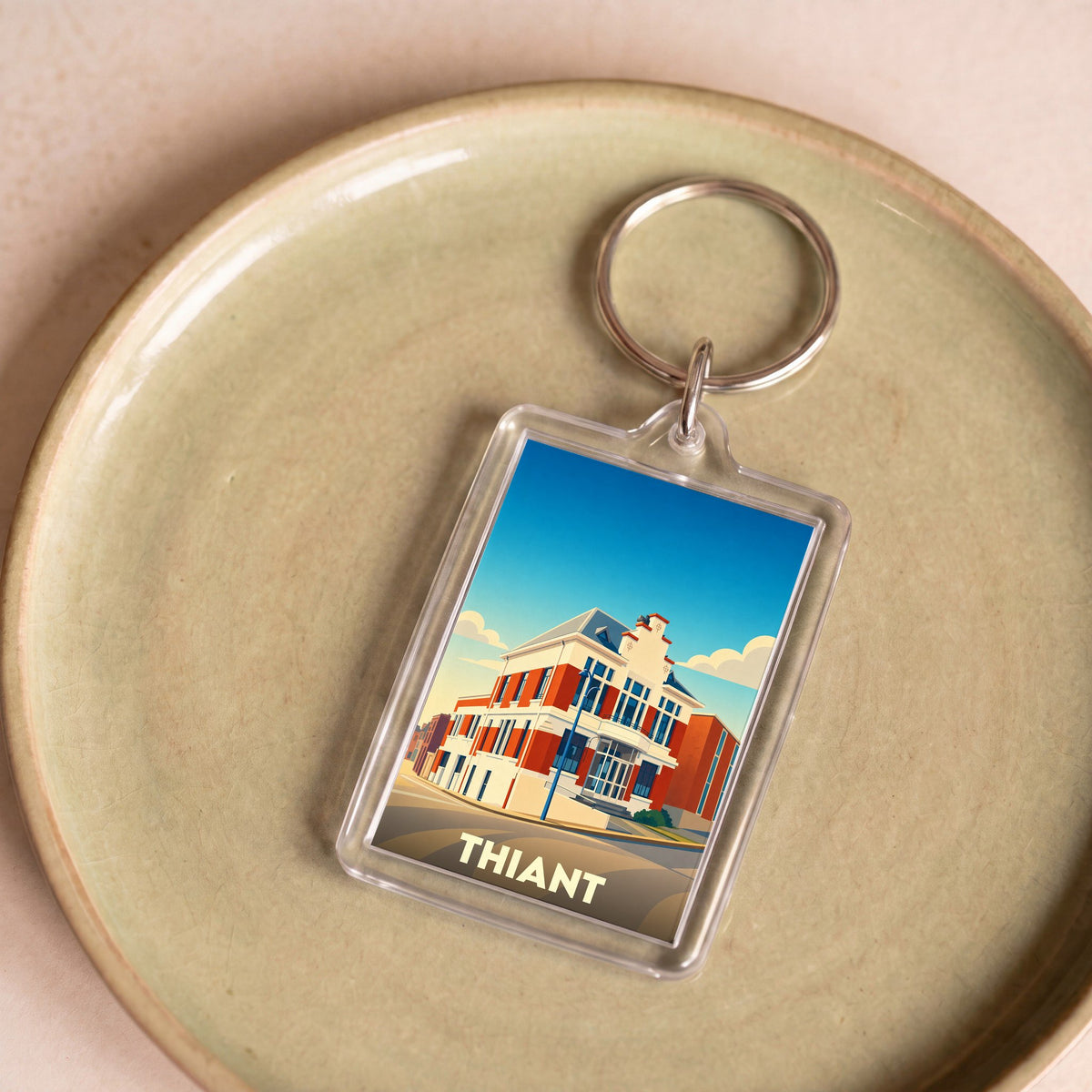 Porte-clés souvenir de la ville de Thiant avec une illustration stylisée de son architecture.
