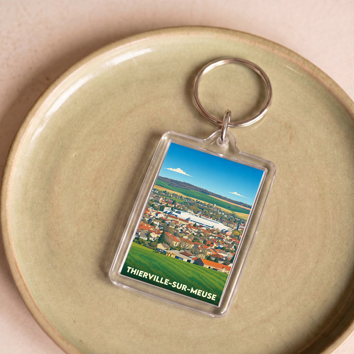 Porte-clés souvenir de la ville de Thierville-sur-Meuse avec une illustration stylisée de son paysage urbain.