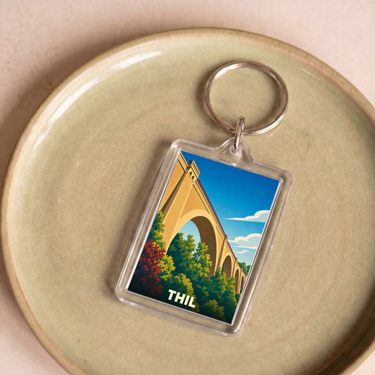 Porte-clés souvenir de la ville de Thil avec une illustration stylisée d'un viaduc.