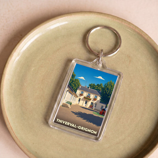 Porte-clés souvenir de la ville de Thiverval-Grignon avec une illustration stylisée d'une maison de ville.