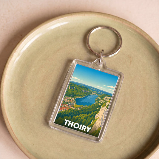 Porte-clés souvenir de la ville de Thoiry avec une illustration stylisée d'un paysage naturel.