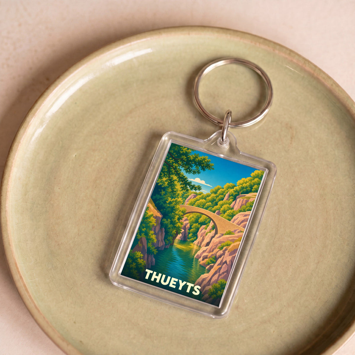 Porte-clés souvenir de la ville de Thueyts avec une illustration stylisée d'un pont en pierre surplombant des gorges.