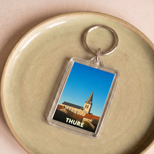 Porte-clés souvenir de la ville de Thuré avec une illustration stylisée de son église.