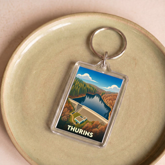 Porte-clés souvenir de la ville de Thurins avec une illustration stylisée d'un barrage et sa retenue d'eau.